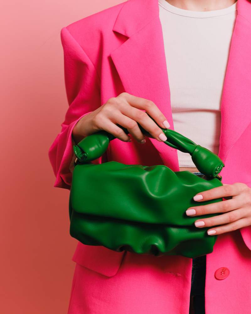 woman on pink carrying classy green handbag